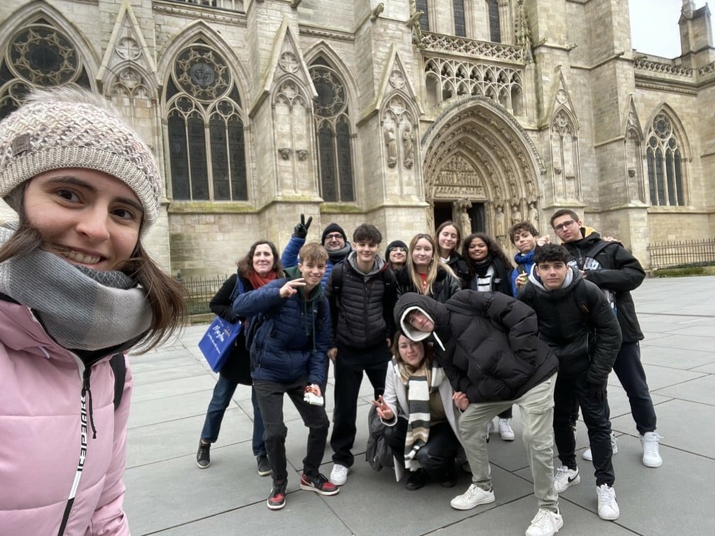 Groupe d'étudiants devant une cathédrale gothique Groupe souriant d'étudiants et adultes prenant un selfie devant la façade gothique d'une cathédrale ou d'une église.